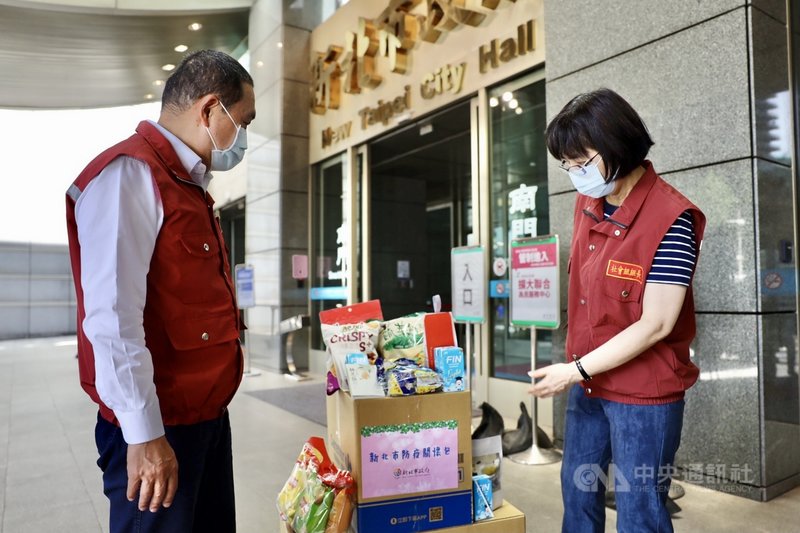 新北市長侯友宜(左)27日請專人專車前往各地集中檢疫所,致贈確診個案關懷包與祝福禮金,在市府車隊出發前,侯友宜也檢視關懷包的內容,除蘋果、零嘴、飲料,還有心靈讀本。(新北市府新聞局提供)中央社記者黃旭昇新北傳真 110年5月27日