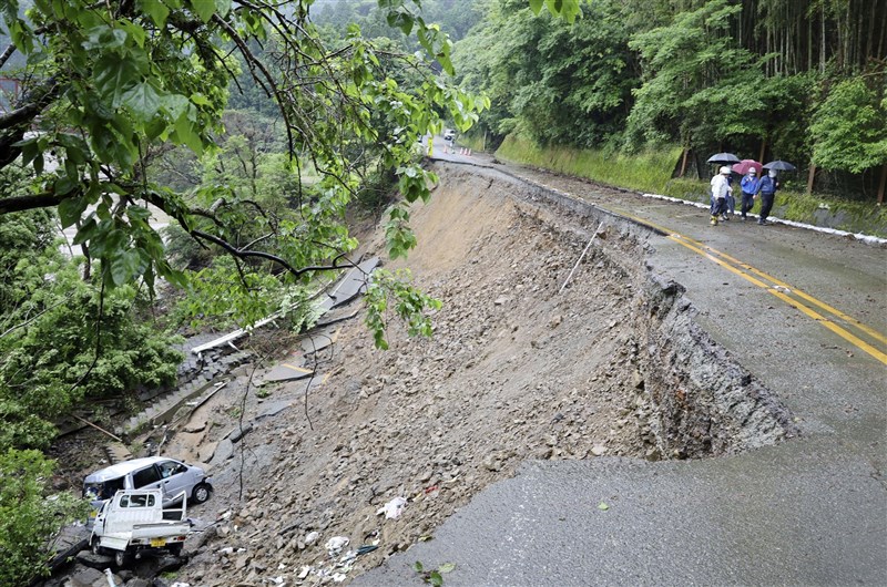 日本九州地區雨勢激烈,熊本縣27日已對約1萬9000人下達避難指示,氣象廳也呼籲民眾對土石流、淹水、河川氾濫等災情提高警戒。圖為21日熊本縣一處道路路基流失崩塌,兩輛車摔落邊坡。(共同社)