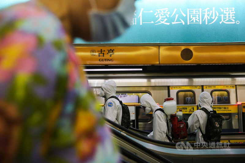 國軍化學兵31日搭乘北捷前往消毒,搭乘手扶梯上樓時與一名戴口罩的捷運乘客對向而過。中央社記者游凱翔攝 110年6月1日