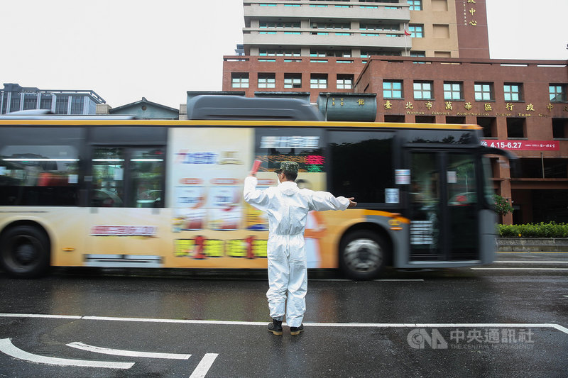 國軍化學兵31日搭乘軍用卡車前往捷運龍山寺站消毒,一名身著防護衣的化學兵特地協助指揮交通。中央社記者游凱翔攝 110年6月1日