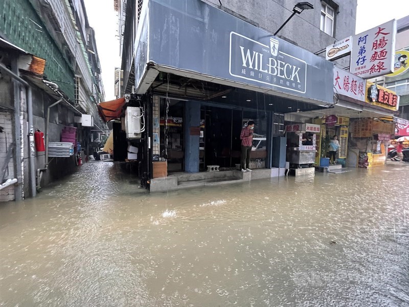 梅雨鋒面接近及颱風彩雲外圍環流影響，4日午後雙北地區出現明顯強降雨，台北市信義區下午達大豪雨等級，多處道路嚴重淹水，永吉路30巷店家業者只能無奈站在門口，等待水退。中央社記者張新偉攝 110年6月4日