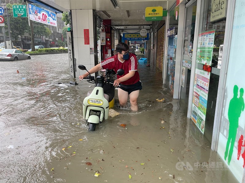 受梅雨鋒面及颱風彩雲外圍環流影響，水利署4日針對台北市文山區、信義區發布淹水一級警戒。圖為信義區永吉路淹水情形，民眾涉水牽機車。中央社記者張新偉攝 110年6月4日