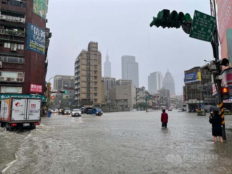 受梅雨鋒面及颱風彩雲外圍環流影響,4日午後瞬間強降雨讓台北市松山區永吉路部分路段淹水,民眾涉水過馬路。中央社記者張新偉攝 110年6月4日