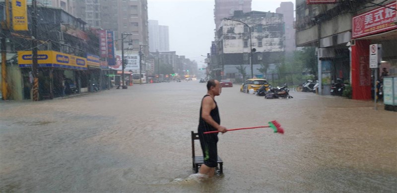受梅雨鋒面及颱風彩雲外圍環流影響,水利署針對台北市文山區、信義區發布淹水一級警戒。圖為民眾在泥濘水中行走,拿掃把準備清理環境。(台北市政府提供)中央社記者陳怡璇傳真 110年6月4日