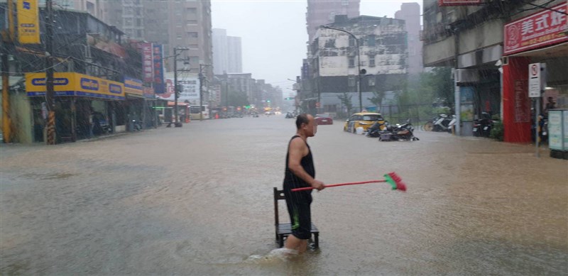 受梅雨鋒面及颱風彩雲外圍環流影響，水利署針對台北市文山區、信義區發布淹水一級警戒。圖為民眾在泥濘水中行走，拿掃把準備清理環境。（台北市政府提供）中央社記者陳怡璇傳真 110年6月4日