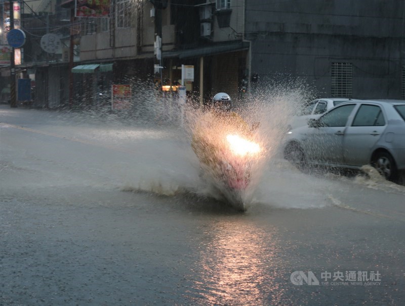 高雄市豪雨不斷,岡山區嘉興路一帶6日清晨積淹水約半個輪胎深,早上外出的人車不清楚路況,涉水通行,路面濺起一尺高的水花。中央社記者王淑芬攝 110年6月6日