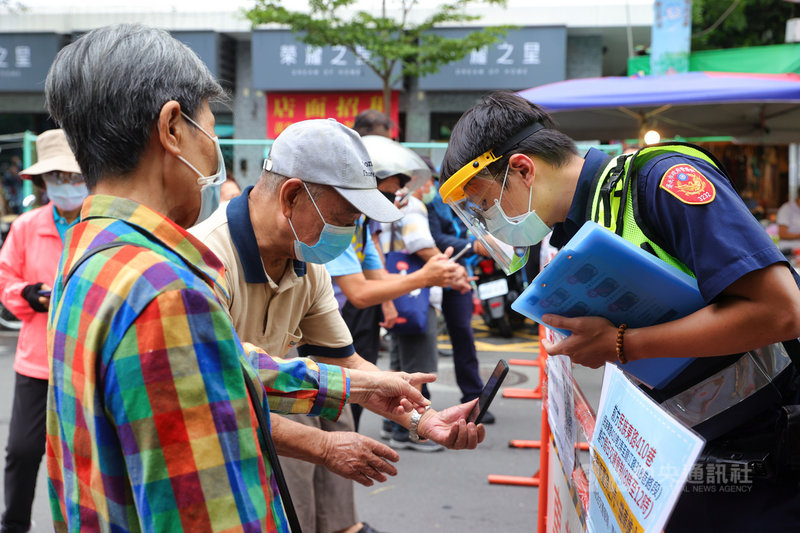 國內COVID-19疫情嚴峻，政府呼籲民眾減少採買次數避免群聚，台北市警方6日在傳統市場入口處管制並進行相關宣導，並協助民眾使用手機完成實聯制。中央社記者謝佳璋攝 110年6月6日