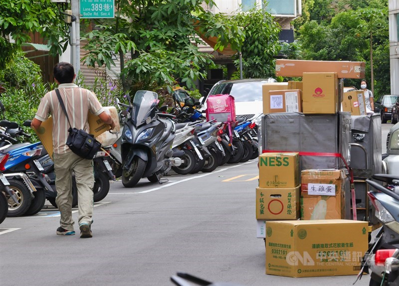 國內COVID-19疫情嚴峻,民眾減少出門在家網購,導致包裹數量大增,宅配通、黑貓宅急便與嘉里大榮等物流業者調整低溫寄送服務。圖為物流人員8日在街頭理貨、送貨。(中央社檔案照片)