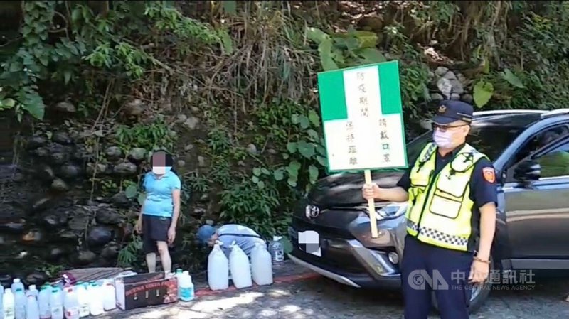 台中谷關地區八仙山森林遊樂區入口處有天然湧泉,14 日端午節陸續有民眾湧入汲取「午時水」,警方前往現場舉牌宣導遵守防疫措施,並進行交通疏導。(民眾提供)中央社記者趙麗妍傳真 110年6月14日