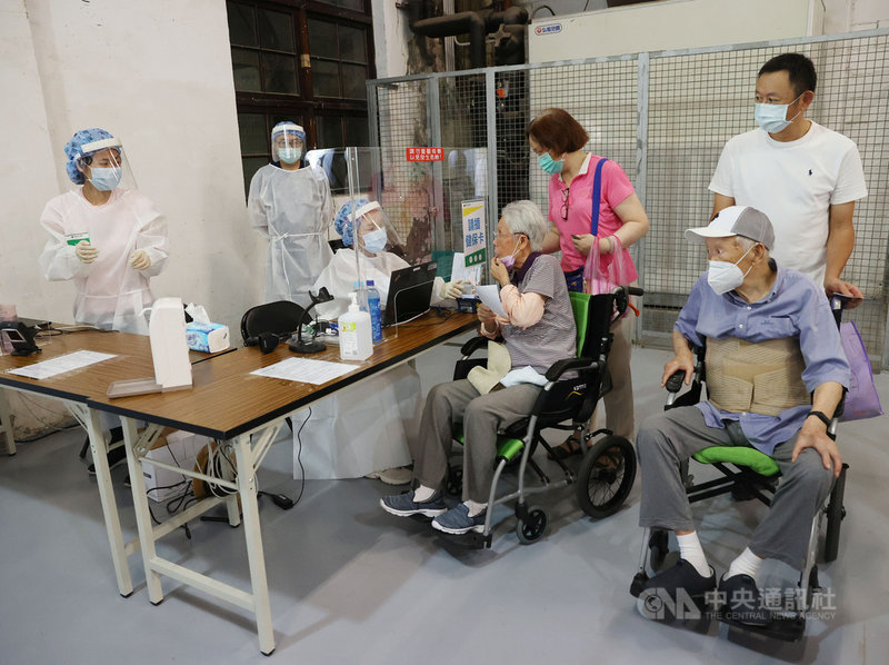 台北市高齡長輩武漢肺炎疫苗接種15日啟動,開放85歲以上長者施打,長者由親人推著輪椅依序排隊報到。中央社記者鄭傑文攝 110年6月15日