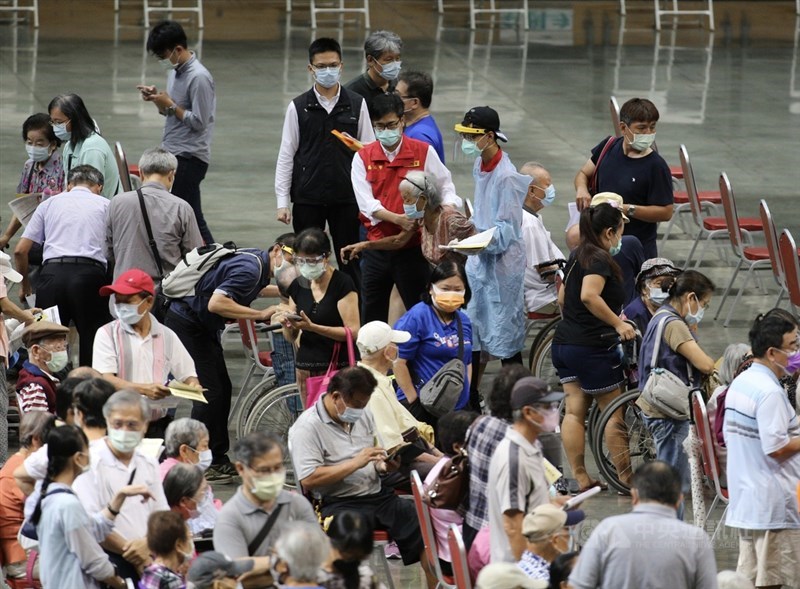 高雄市高齡長輩疫苗接種15日啟動，首波是87歲以上長者，醫護採「宇美町式」讓長輩排排坐，市長陳其邁（後中，紅背心者）上午前往漢神巨蛋體育館關切長輩們接種疫苗情形。中央社記者董俊志攝 110年6月15日