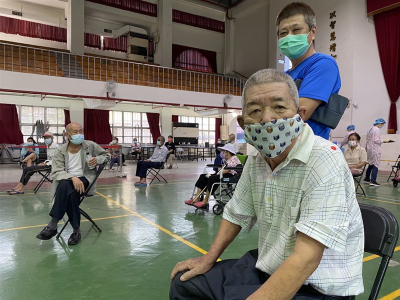 高雄路竹高中疫苗接種站17日意外上演小學同學重逢記,在兒子陪同下前來打疫苗的87歲長輩洪允可(前右),意外被才剛坐下的老同學洪壁錄(前右2)認出,兩人也開始話當年。(高雄市政府提供)中央社記者洪學廣傳真 110年6月18日