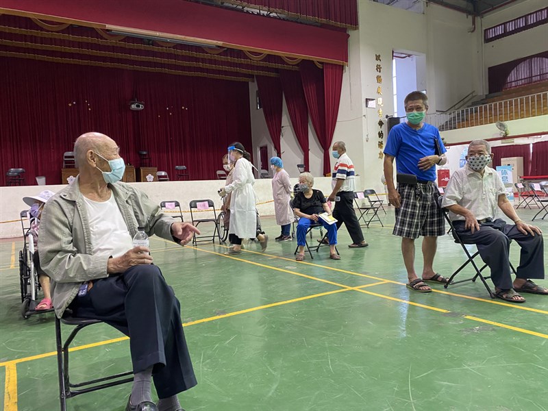 高雄路竹高中疫苗接種站17日有名87歲長輩洪壁錄(前左)獨自到場,經引導入座後,他隨即跟隔壁另一位長者洪允可(前右)熱情打起招呼,原來兩位同齡阿公竟然是小學同學,意外在打疫苗時重逢相會。(高雄市政府提供)中央社記者洪學廣傳真 110年6月18日