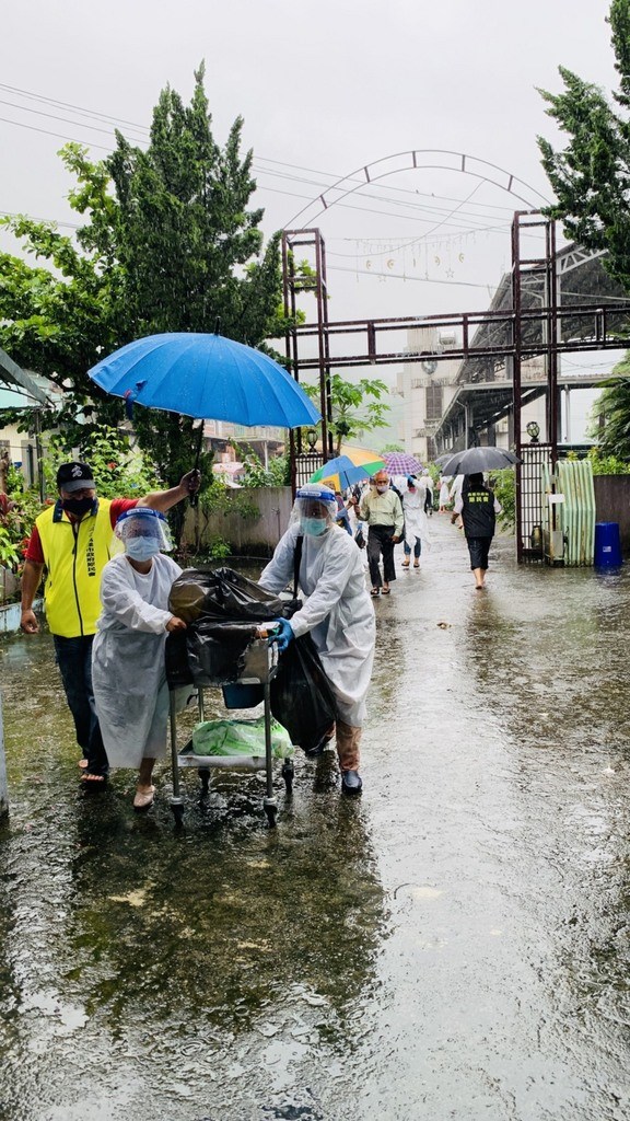 高雄21日開放第三波長者接種疫苗,受鋒面大雨影響,設在籃球場的那瑪夏區疫苗接種站上午一度積水5公分高,原民會和區公所人員緊急應變,攙扶長者撐傘遮雨移往民權教會施打疫苗。(高市原民會提供)中央社記者洪學廣傳真 110年6月21日