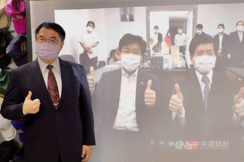 台南市長黃偉哲(左)23日下午與日本平戶市長黑田成彥(投影布幕前左)跨海視訊,互相行銷特產,進行美食外交。(台南市政府提供)中央社記者楊思瑞台南傳真 110年6月23日