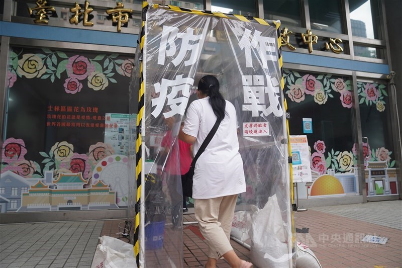 台北市士林區行政中心外設置隧道式噴霧消毒,進入洽公的民眾必須徹底消毒,通道口貼著「防疫作戰」提醒民眾防疫不鬆懈。中央社記者徐肇昌攝 110年6月23日