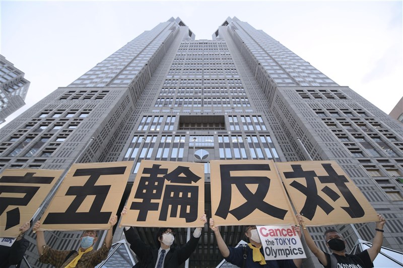 日本東京每次一解除緊急事態,疫情又立即升溫。日媒預料「第5波」疫情恐在東奧期間來襲。圖為東京都政府大樓外民眾舉牌示威抗議舉辦奧運。(共同社)