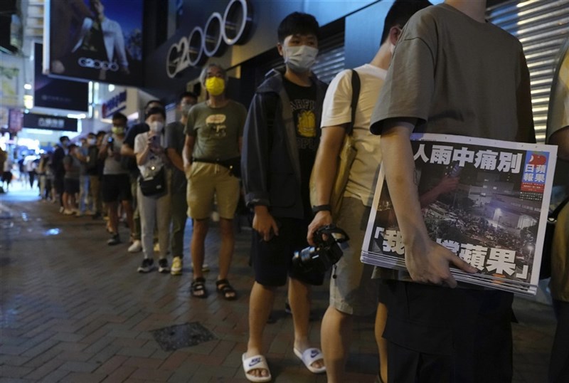 26年前創刊的香港蘋果日報被迫停刊,24日出版最後一份報紙,以「港人雨中痛別,我哋(們)撐蘋果」為頭版標題,大批民眾在街頭排隊購買。(美聯社)