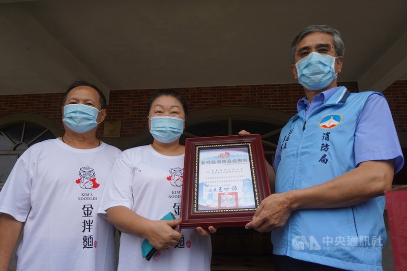 COVID-19疫情嚴峻,為感謝第一線防疫人員的付出,莉豐建設公司董事長張莉(中)和金拌麵董事長崔文柏(左)25日聯合捐贈拌麵和燕仔草茶給金門縣消防局,副局長呂英華(右)也回贈感謝狀。中央社記者黃慧敏攝 110年6月25日