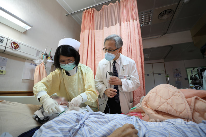 家住台東縣成功鎮的吳姓漁民因唇癌末期入住花蓮慈濟醫院安寧病房,為完成他想回家的心願,醫療團隊決定陪他跨縣市圓夢;吳男因有重聽情形,緩和醫療中心主任王英偉(右)特別透過助聽器的麥克風,與吳男確認出發前的準備。(花蓮慈濟醫院提供)中央社記者張祈傳真 110年6月25日