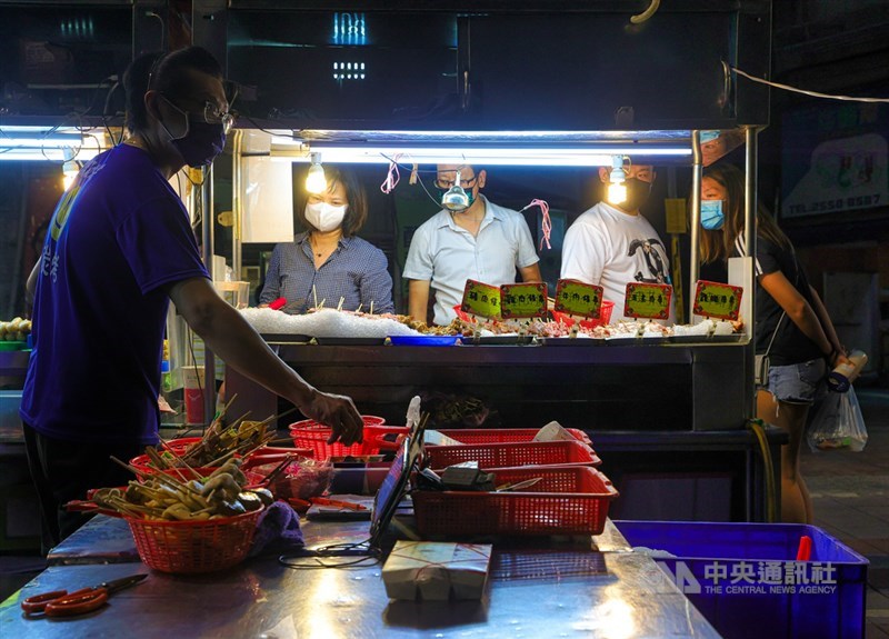 台北寧夏夜市29日晚間「微解封」第一天,戴著口罩的碳烤攤老闆忙著料理客人餐點,外頭還有民眾在攤位前選購食材。中央社記者謝佳璋攝 110年6月29日
