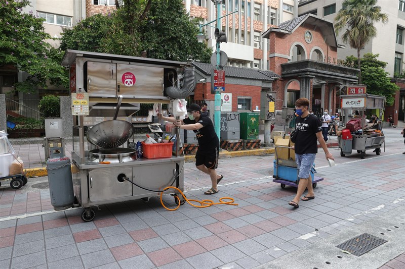 台北寧夏夜市29日起「微解封」,為避免消費者過度群聚和停留時間過長,採「單邊攤商營業、得來速外帶型態」提供外帶服務,且攤商與消費者皆須配合實聯制、保持安全距離、全程配戴口罩等防疫措施。圖為寧夏夜市部分攤商下午推出攤車,準備營業。中央社記者謝佳璋攝 110年6月29日