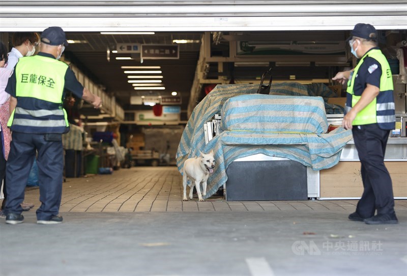台北市環南市場經篩檢後,發現有41名攤商PCR陽性,北市府2日宣布即刻休市3天並清消場域,攤商火速撤離,保全人員在拉上鐵捲門前叫小狗趕快出來。中央社記者鄭清元攝 110年7月2日
