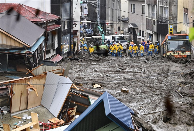 日本靜岡縣熱海市4日發生土石流,警消在被黑色土石淹沒的道路上搜救。(共同社)