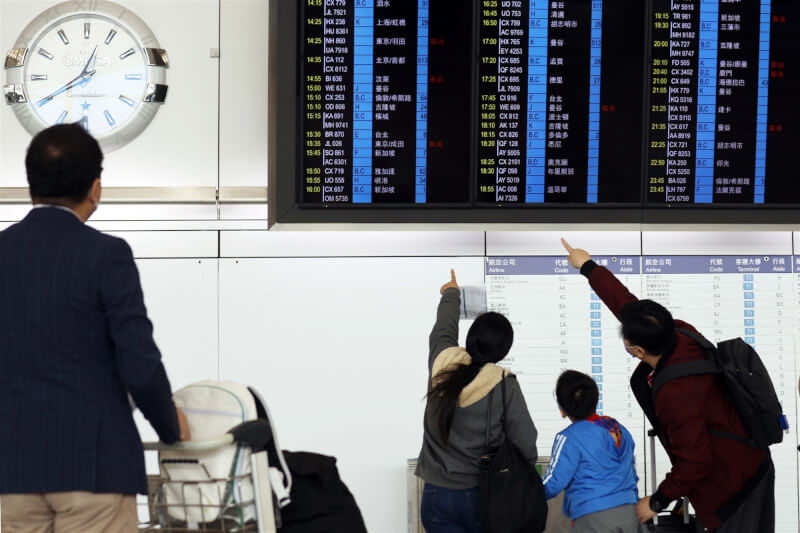 圖為香港國際機場旅客在電子看板前觀看航班訊息。（中新社）