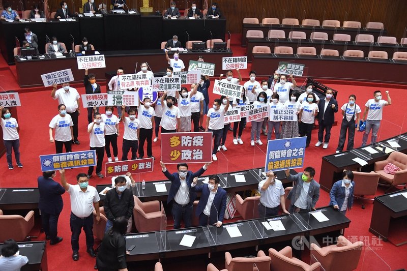 國民黨立法院黨團建請召開臨時會審議公投法修正草案,納不在籍投票。立法院7日召開全院委員談話會處理,經表決後,因民進黨團反對,國民黨團提案未通過。圖為表決時國民黨立委(後排白衣)與民進黨立委(前排)互相以標語表達立場。中央社記者王飛華攝 110年7月7日