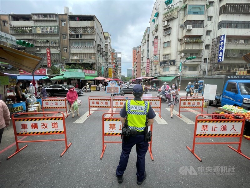 中央流行疫情指揮中心宣布,全國第三級警戒延到7月26日,但民生消費部分行業適度鬆綁。圖為8日上午警察在主要道路口設柵欄管制人流。中央社記者王飛華攝 110年7月8日
