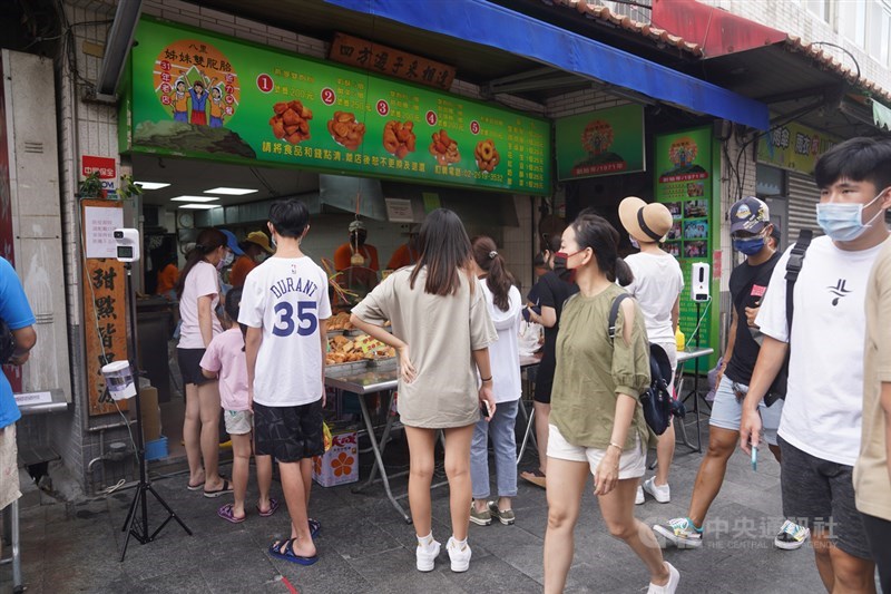 中央流行疫情指揮中心公布全國3級警戒延長至7月26日,同時自13日起可有條件放寬部分場域管制措施。不過「微解封」還沒上路,新北八里老街10日午後已出現出遊潮,不少人在小吃店外排隊。中央社記者徐肇昌攝 110年7月10日