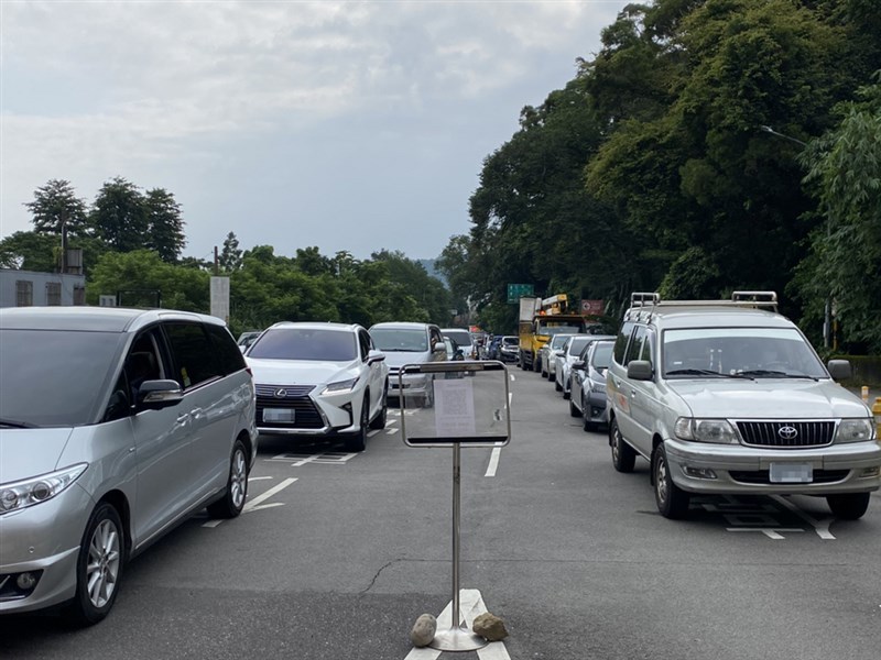石門水庫園區13日微解封首日實施入園小客車400輛、機車100輛總量管制,工作人員表示,入園須實聯制、量額溫,因此作業較慢,上午開始停車場入口就有塞車情形,約11時達車輛滿額。(讀者提供)中央社記者葉臻傳真 110年7月13日
