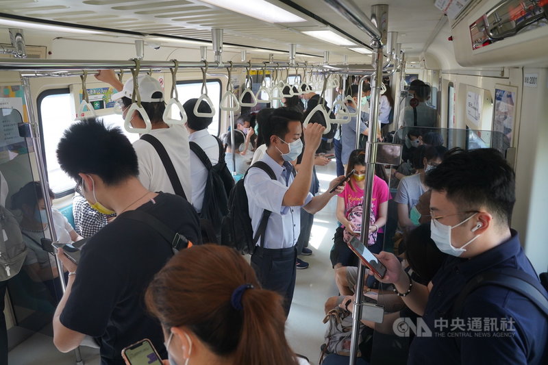 中央流行疫情指揮中心宣布全國第3級警戒延至26日,但13日起適度鬆綁部分措施實施「微解封」。微解封首日,民眾搭捷運通勤上班,在車廂內滑手機打發時間。中央社記者徐肇昌攝 110年7月13日