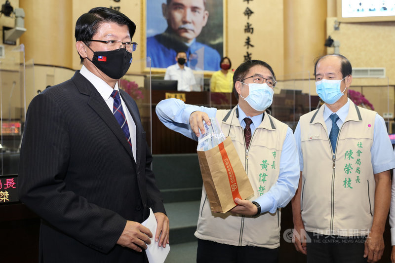 國民黨台南市議員謝龍介(左)14日在議會市政總質詢時把裝有新台幣100萬元現金的紙袋交給市長黃偉哲(中),盼市府用來幫助弱勢學童。右為社會局長陳榮枝。(台南市議會提供)中央社記者楊思瑞台南傳真 110年7月14日