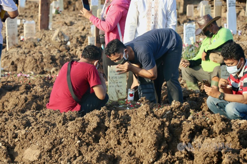 印尼許多地方持續面臨醫療氧氣不足危機，部分患者因缺氧而死亡。圖為印尼民眾10日在墓園訣別親人，不捨親吻墓碑。（中央社檔案照片）