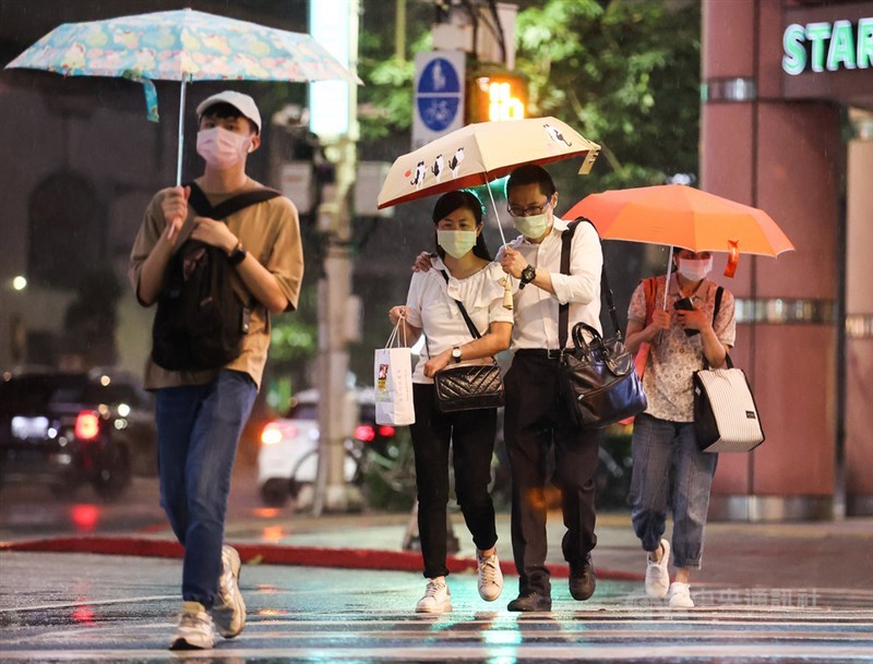 颱風烟花逼近,中央氣象局21日晚間9時20分針對北北基等6縣市發出大雨特報。台北市區入夜後風雨變得明顯,街頭有民眾在雨中共撐一把傘。中央社記者鄭清元攝 110年7月21日