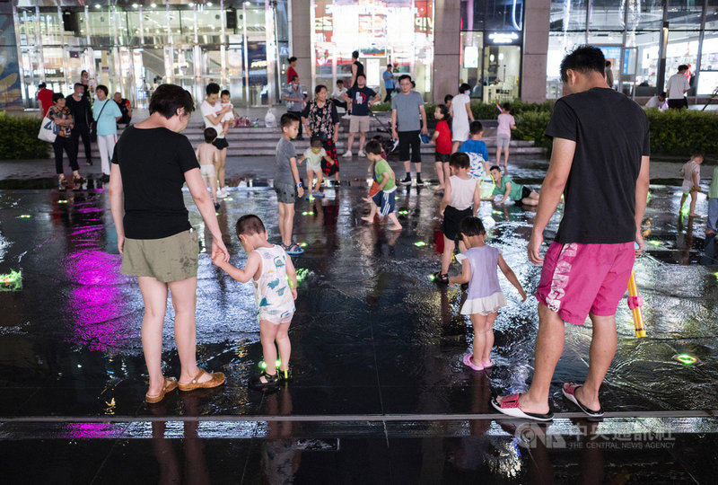 中國5月底開放生育三孩後,中國國家衛健委官員21日指出,今年的出生人口和生育水平仍然呈現走低的趨勢。圖為20日晚間,市民帶著孩子在北京朝陽區望京小街的噴泉玩耍。(中新社提供)中央社 110年7月21日