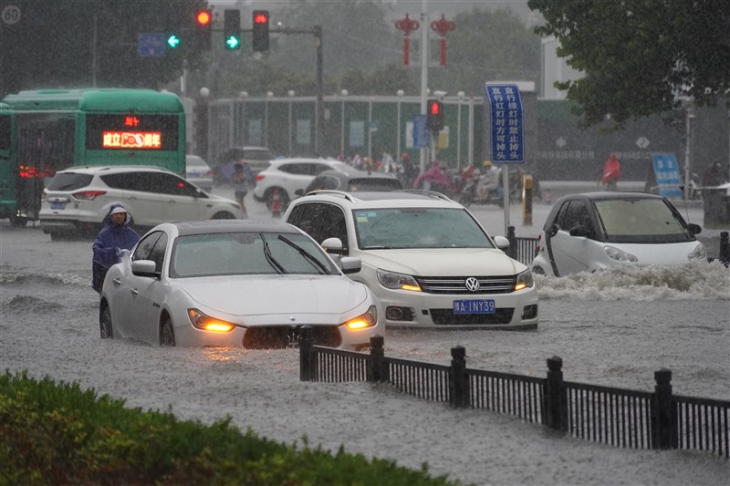中國河南省20日遭逢大暴雨,致使當地交通中斷受阻。鄭州機場21日中午12時前不接受進港航班。圖為鄭州民眾駕車行駛在積水路面。(中新社)