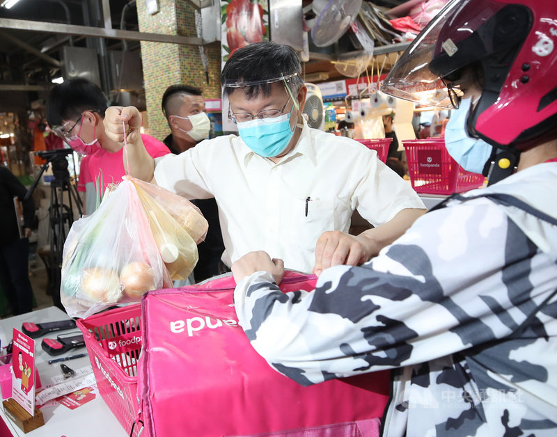 為協助傳統市場轉型,台北市政府勞動局攜手產業局推出「不用上市場、生鮮送你家」方案,市長柯文哲(中)21日上午赴光復市場視察,幫忙將商品放入外送員的袋子裡。中央社記者張新偉攝 110年7月21日