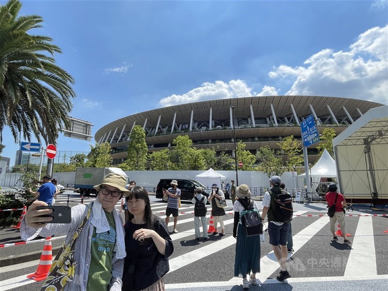 東京奧運開幕式無觀眾入場,民眾在主場館新國立競技場附近拍照留念。中央社記者楊明珠東京攝 110年7月23日
