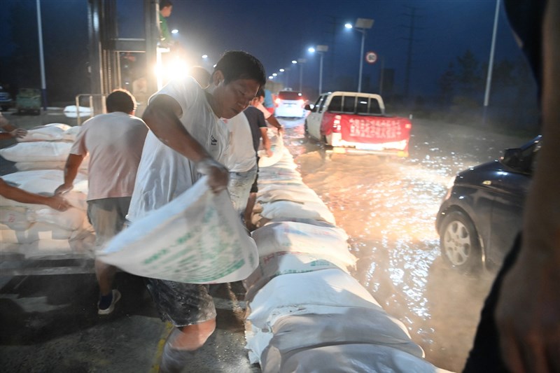 河南連日大暴雨,23日衛河河南新鄉段等部分河段出現險情。當日夜間,當地村民在G107國道新鄉段壘築堤壩抵禦洪水。(中新社提供)中央社 110年7月24日