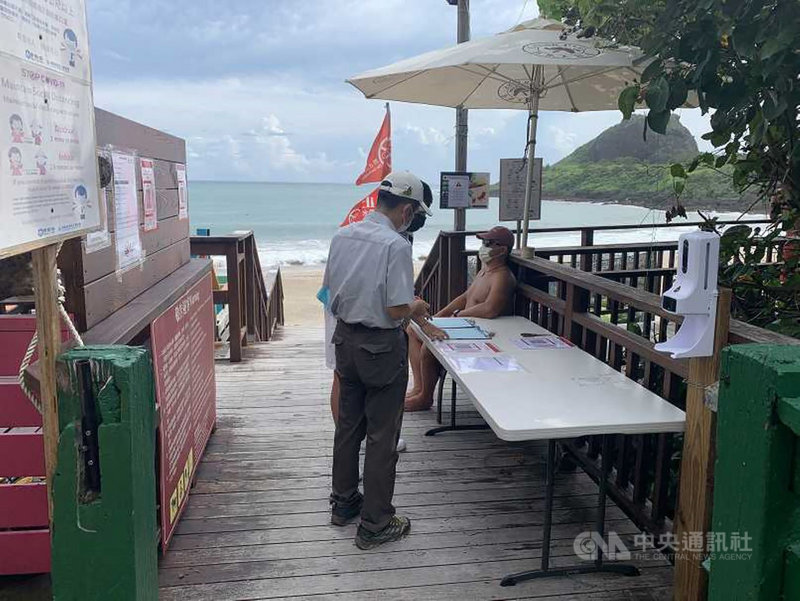 全台疫情警戒標準27日起降為2級,墾丁國家公園管理處與在地協會及業者攜手合作,完成相關防疫整備,首波自即日起開放5處沙灘。圖為開放的小灣沙灘採單一入口,民眾進入須量測體溫、消毒並完成實聯制登記。(墾管處提供)中央社記者郭芷瑄傳真 110年7月27日