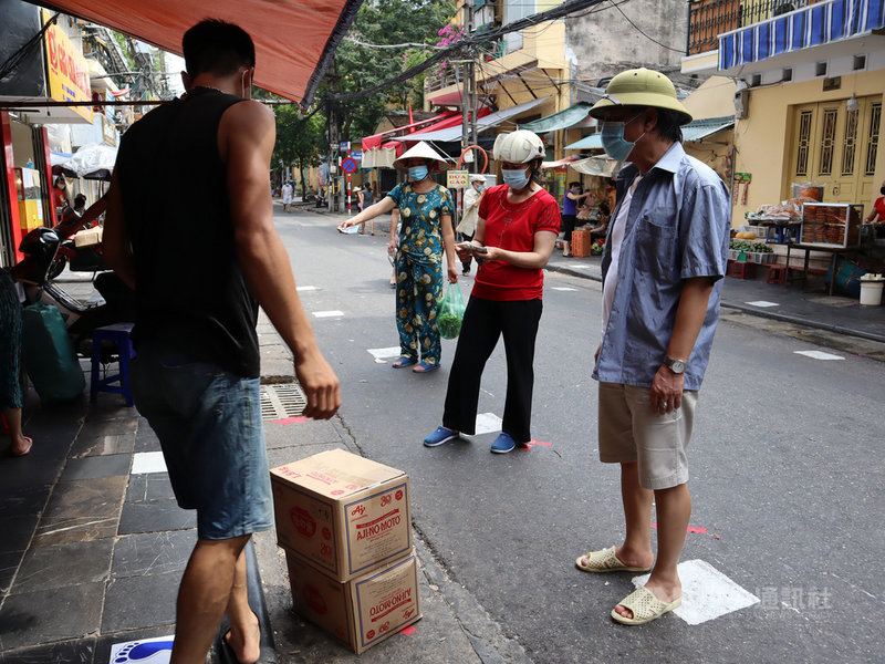 河內市阮善述街市場管理單位為了防疫在地上畫出一塊塊的白色方形,每個相隔2公尺,讓民眾可以保持社交距離排隊購物。中央社記者陳家倫河內攝 110年7月28日