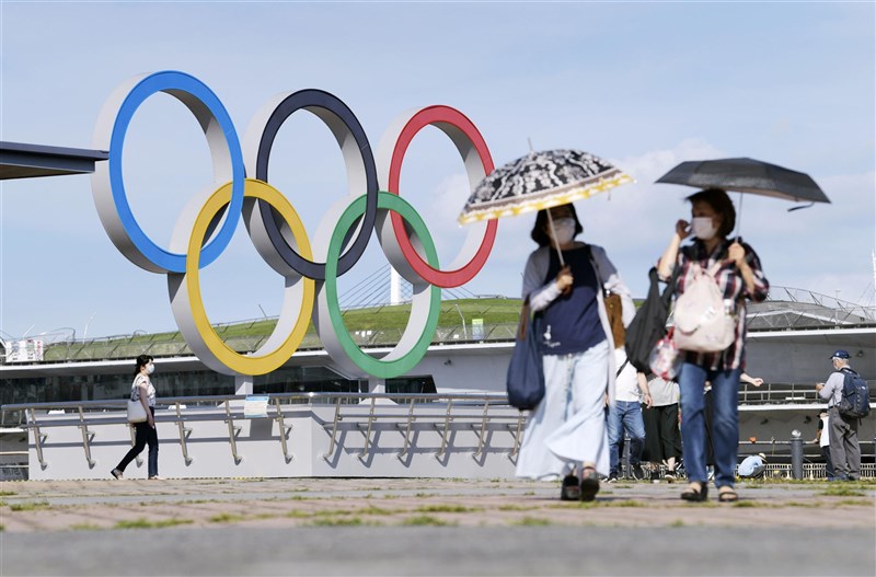 日本中央政府擬30日將首都圈3縣(神奈川縣、埼玉縣、千葉縣)納入緊急事態宣言對象地區。圖為16日民眾行經神奈川縣橫濱市的奧運標誌旁。(共同社)