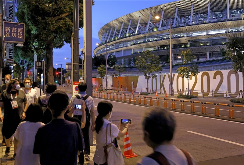 東京奧運選手村有8成以上運動員和教練接種疫苗,且大會嚴格限制移動,與場外逐漸鬆續防疫的民眾形成巨大對比。圖為27日晚間在東奧主場館國立競技場附近的人潮。(共同社)