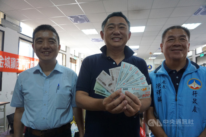金門縣長楊鎮浯(中)29日宣布,將普發縣民每人新台幣3000元紓困現金,並在疫情再次降級後,加碼發給每個縣民振興券3000元,待縣議會審議預算通過,即可發放。圖為楊鎮浯手拿2020年金門振興券。中央社記者黃慧敏攝 110年7月29日
