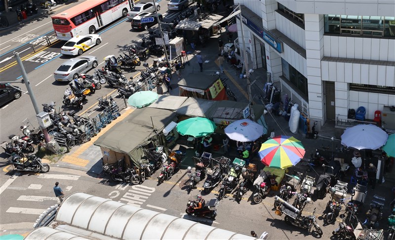 韓國中央防疫對策本部通報,29日新增1710例確診,已連續24天破千例。圖為26日首爾東大門市場外排滿了等候取貨的外送員。(韓聯社)