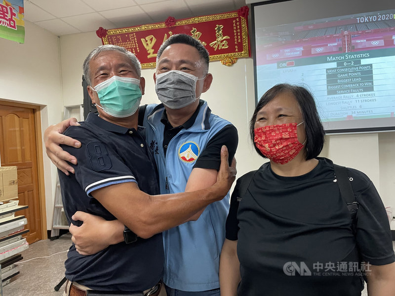 金門出身的羽球好手李洋31日與搭檔王齊麟出征東京奧運羽球男雙冠軍戰,成功搶下金牌,金門縣長楊鎮浯(中)開心地和李洋伯父李開陣(左)相擁。右為金門縣體育會理事長唐麗輝。中央社記者黃慧敏攝 110年7月31日