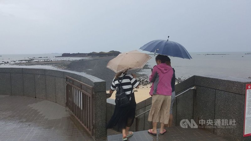 國內COVID-19疫情警戒降至2級,澎湖縣政府指出,澎湖各觀光景點大都採總量管制,最熱門的澎湖北寮摩西分海步道受到雨勢影響,31日上午退潮時,只見有少部分的遊客在雨中持傘下海體驗。中央社 110年7月31日